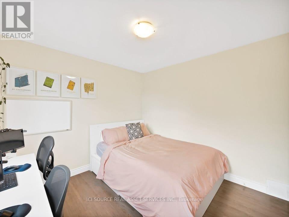 A bedroom with a bed, desk, chair, and pictures on the wall.