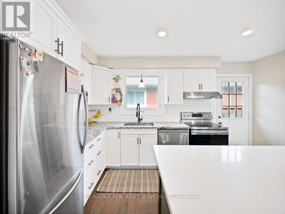 A kitchen with white cabinets and a stainless steel refrigerator.