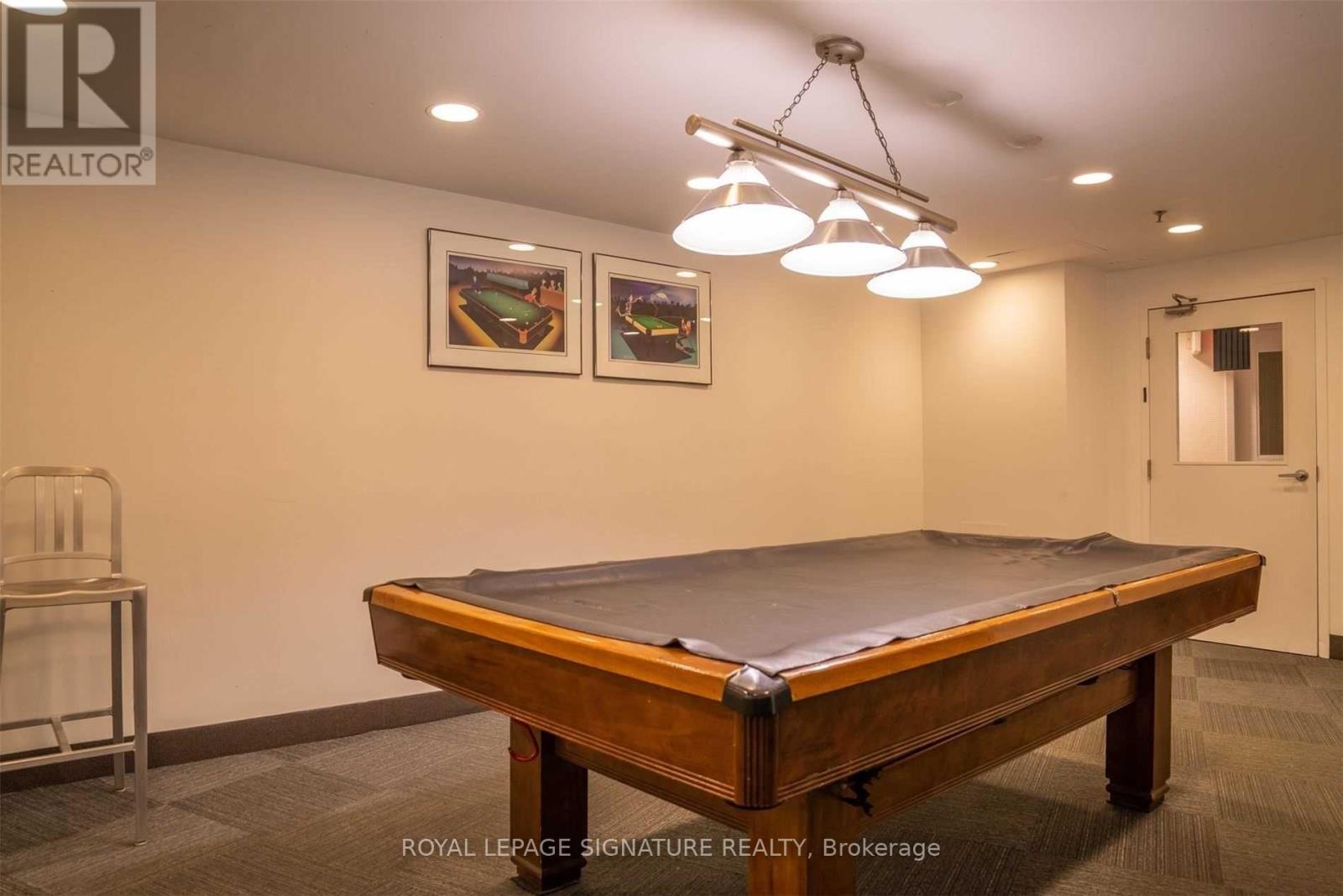 A pool table in a room with a chair and pictures on the wall.