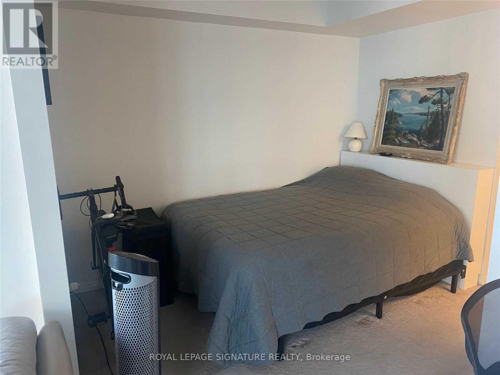 A bedroom with a bed, a chair, and a painting on the wall.