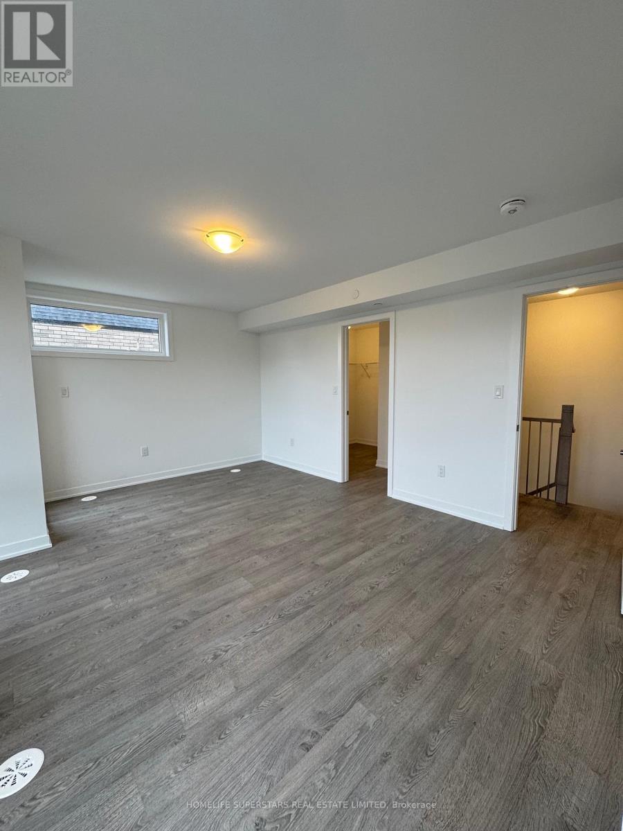 A spacious room with wooden flooring and white walls.