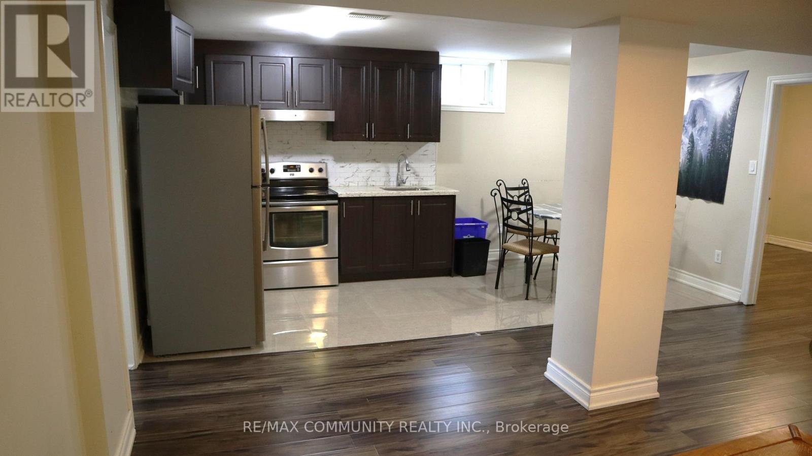 A kitchen with a refrigerator, oven, and a dining table with chairs.