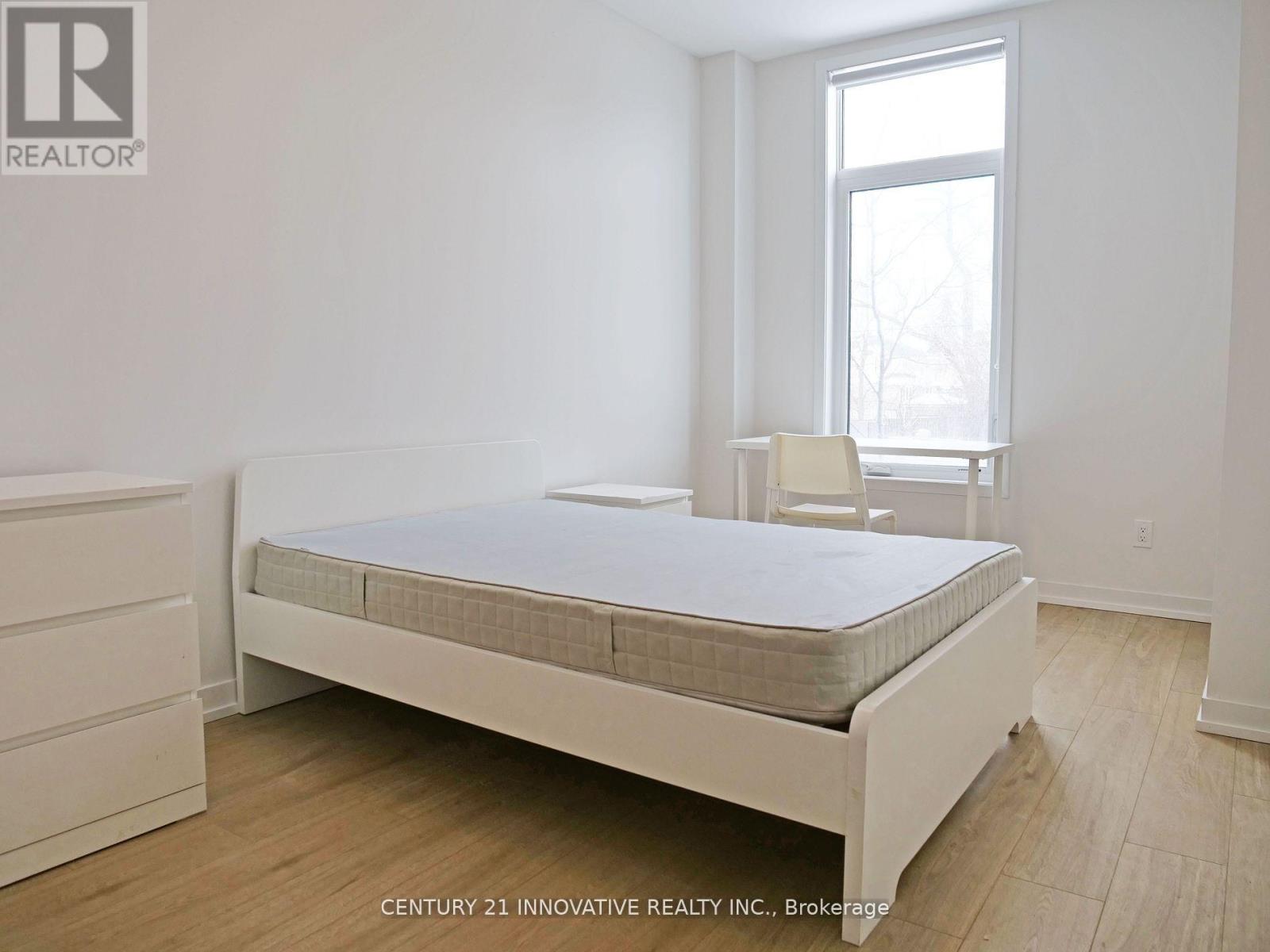 A bedroom with a bed, a chair, and a window.