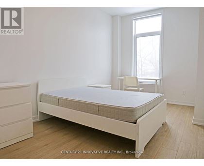 A bedroom with a bed, a chair, and a window.
