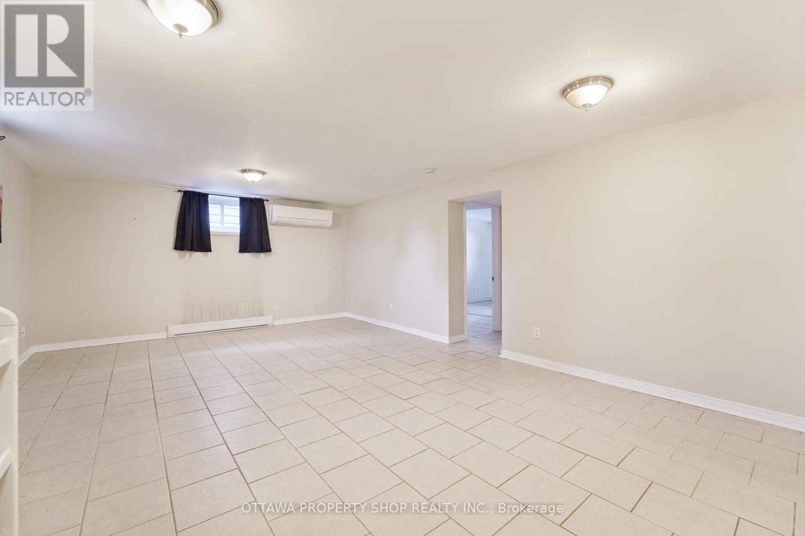 A spacious room with a tiled floor and a doorway leading to another room.
