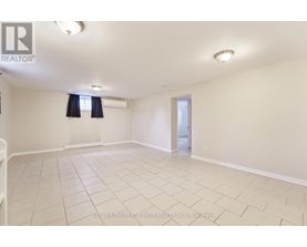 A spacious room with a tiled floor and a doorway leading to another room.