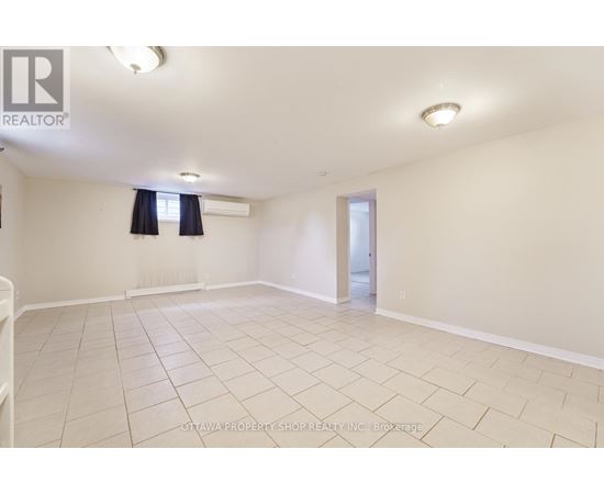 A spacious room with a tiled floor and a doorway leading to another room.