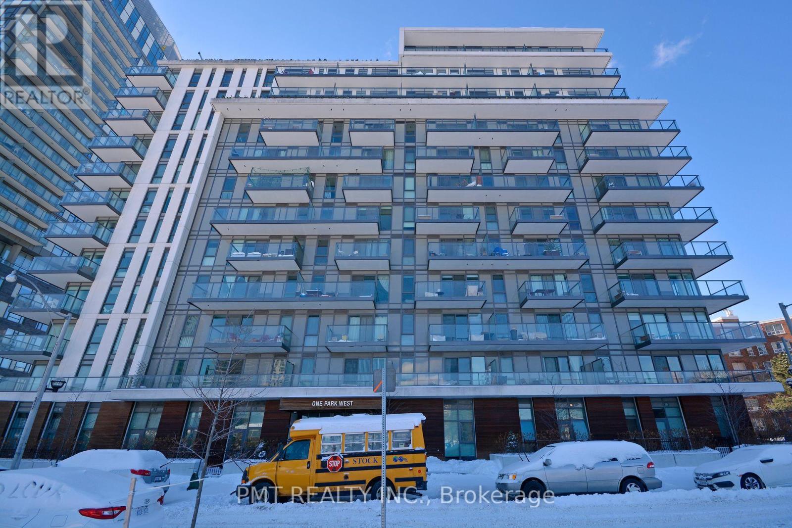A tall building with a glass facade and a yellow van parked in front.