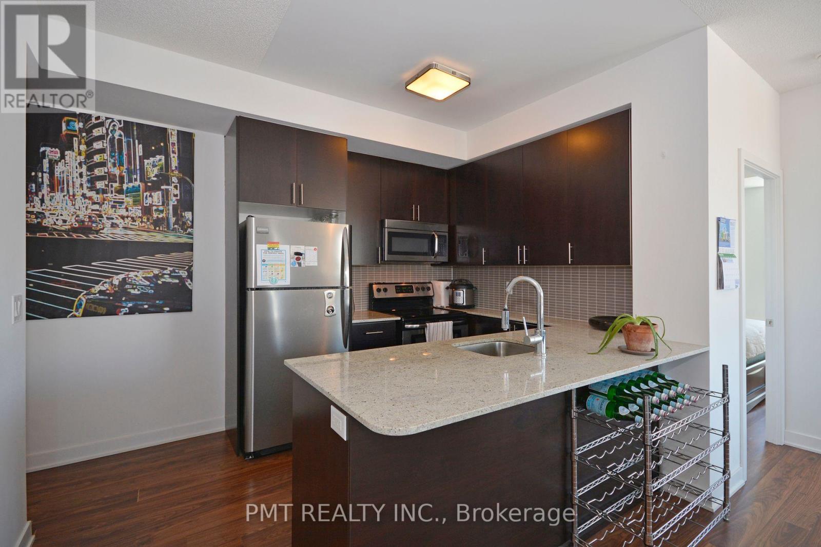 A kitchen with a refrigerator, microwave, and oven.