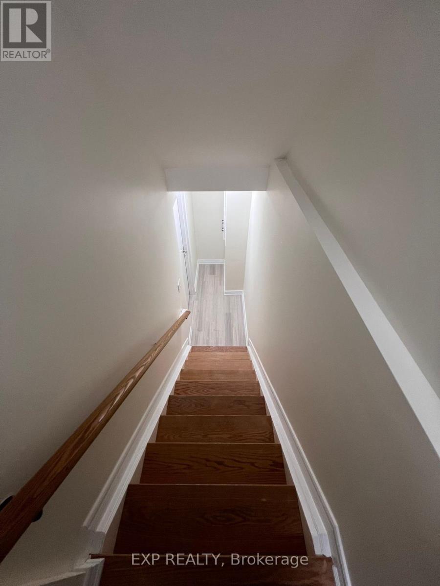 A long hallway with a staircase leading to a landing with a white door.