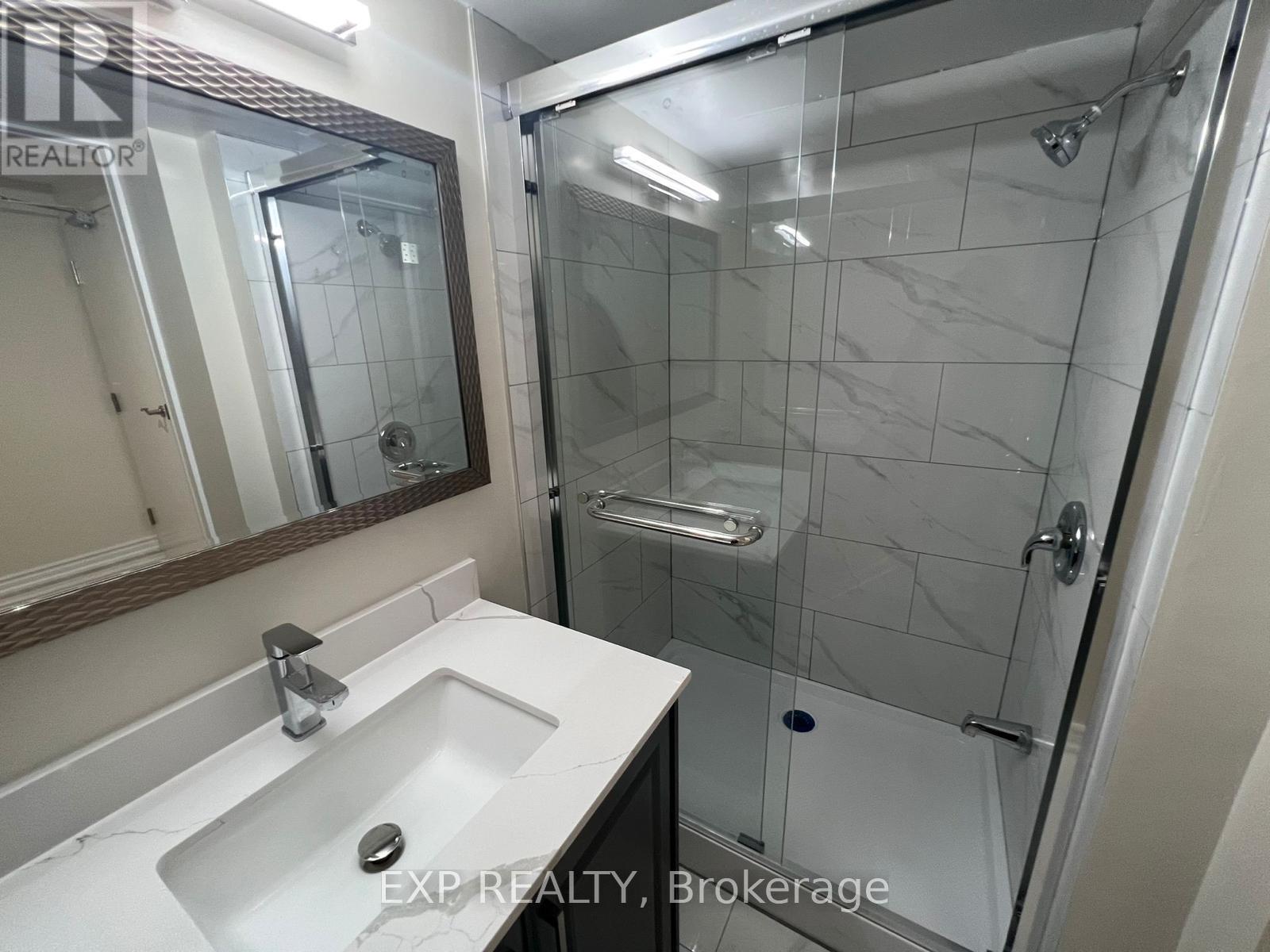 A bathroom with a sink, mirror, and glass shower stall.