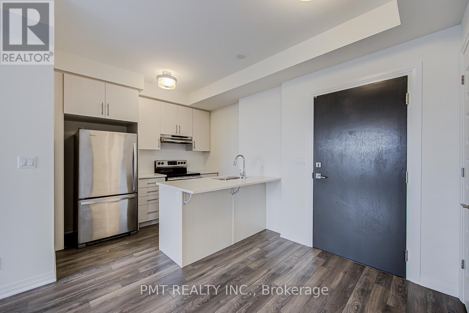 A kitchen area with a refrigerator, stove, and cabinets.