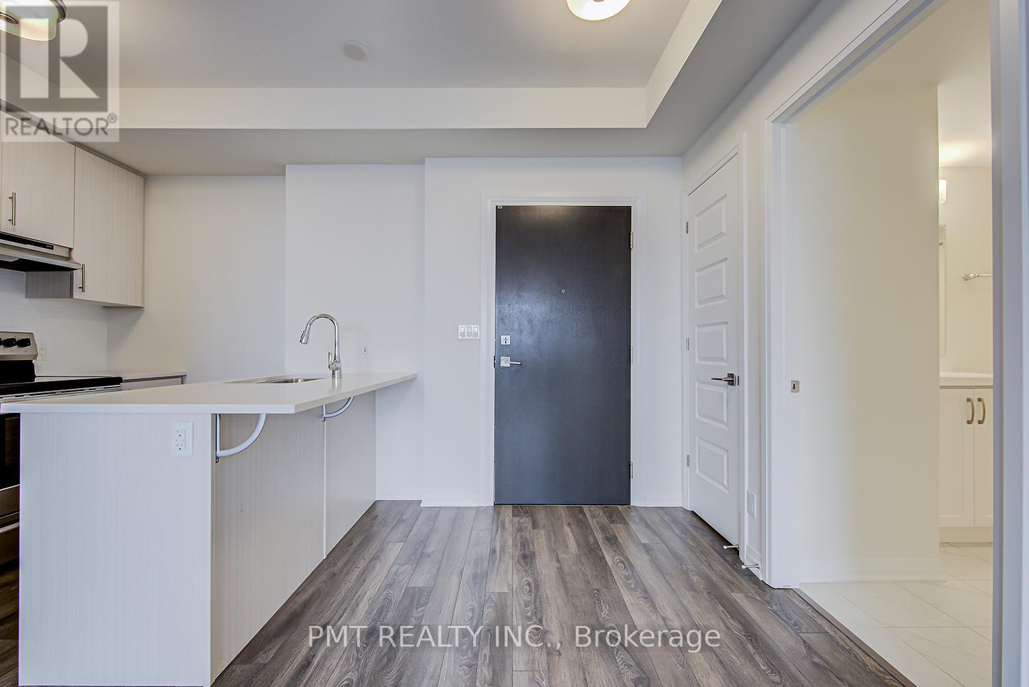 A kitchen with white cabinets and a black door.