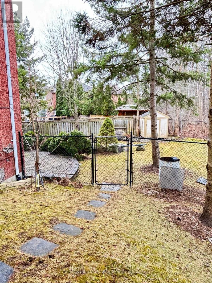 A backyard with a fence, a trash can, and a pathway.