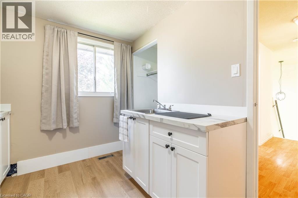 A small, clean, and well-lit kitchen with white cabinets and a window.