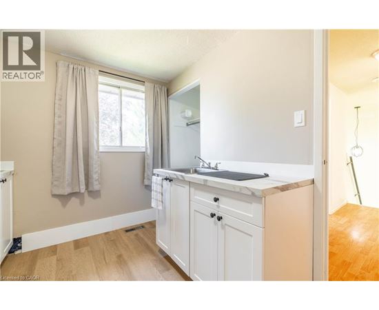A small, clean, and well-lit kitchen with white cabinets and a window.