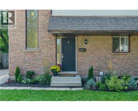 A house with a black front door and a small garden in front.