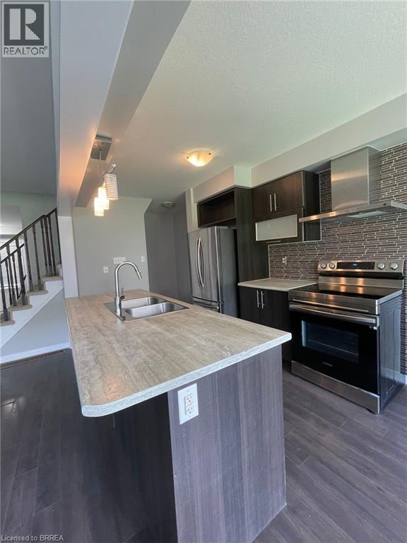 A modern kitchen with a wooden island and stainless steel appliances.