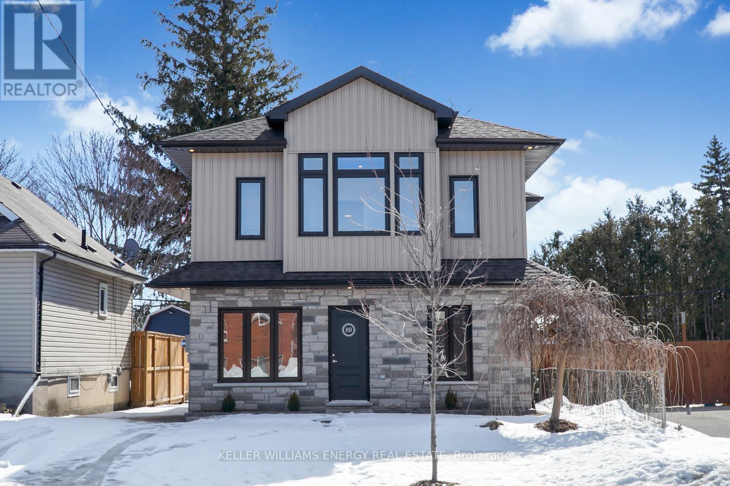 A house with a stone facade and a black door is surrounded by snow.