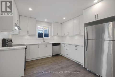 A modern kitchen with white cabinets and a stainless steel refrigerator.