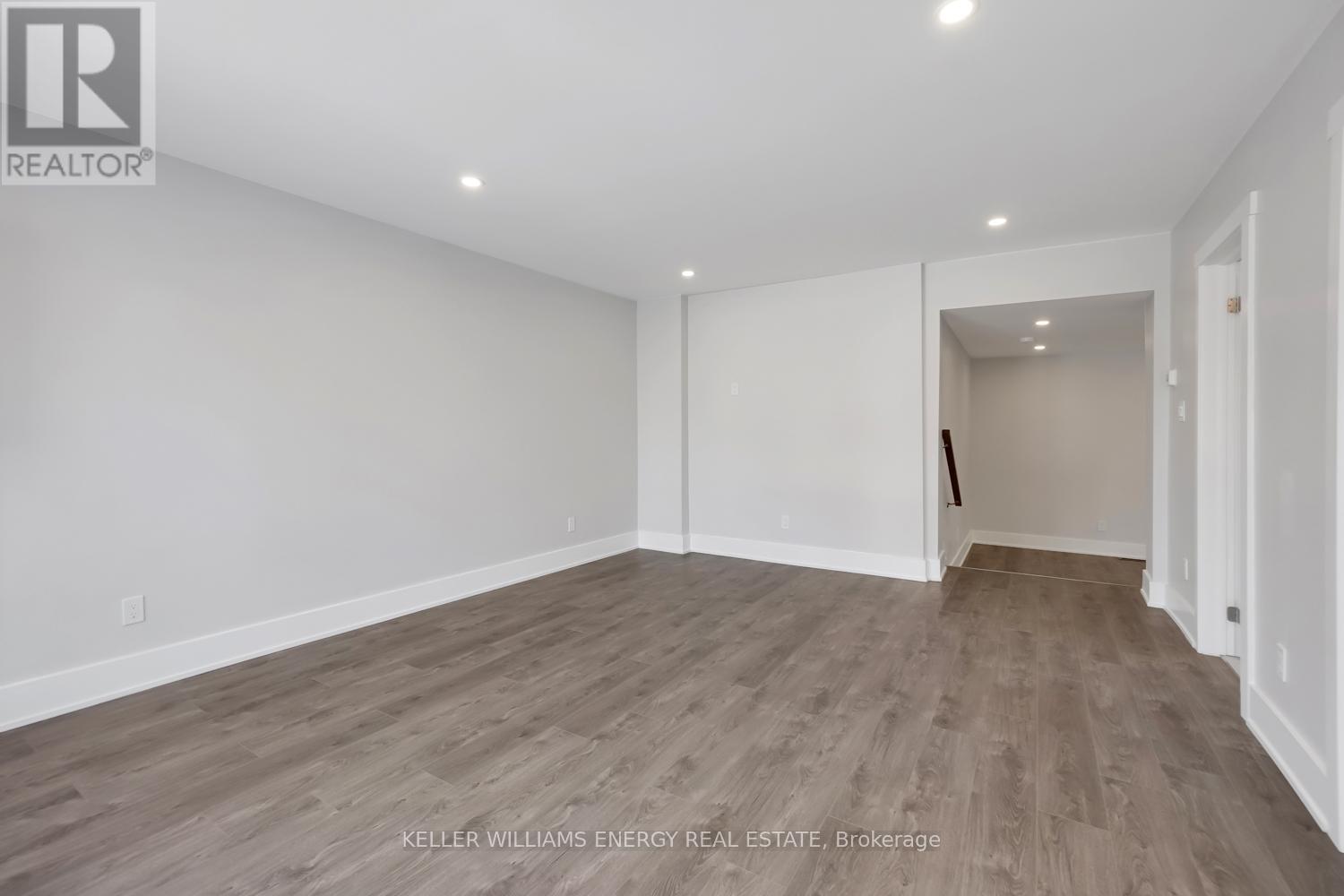 A spacious room with wooden flooring and white walls.