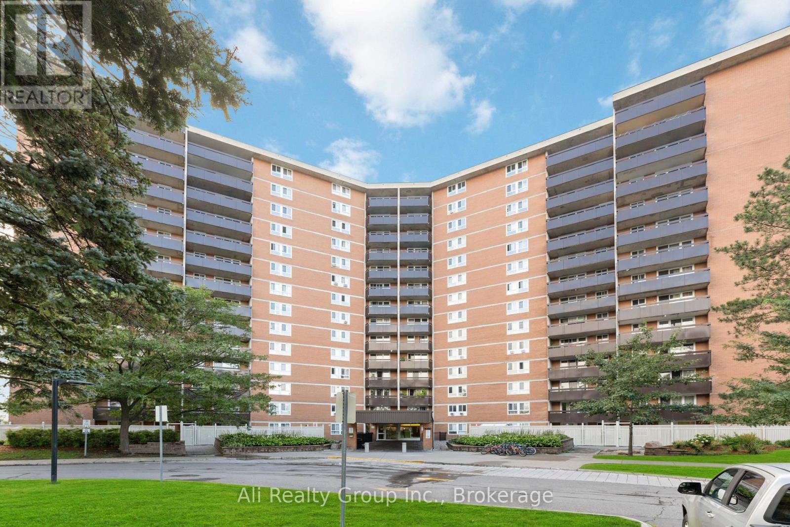 A tall apartment building with a parking lot in front.
