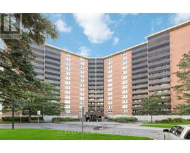 A tall apartment building with a parking lot in front.