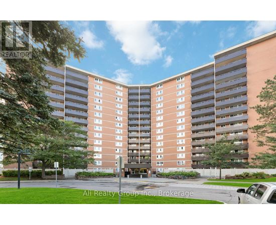 A tall apartment building with a parking lot in front.