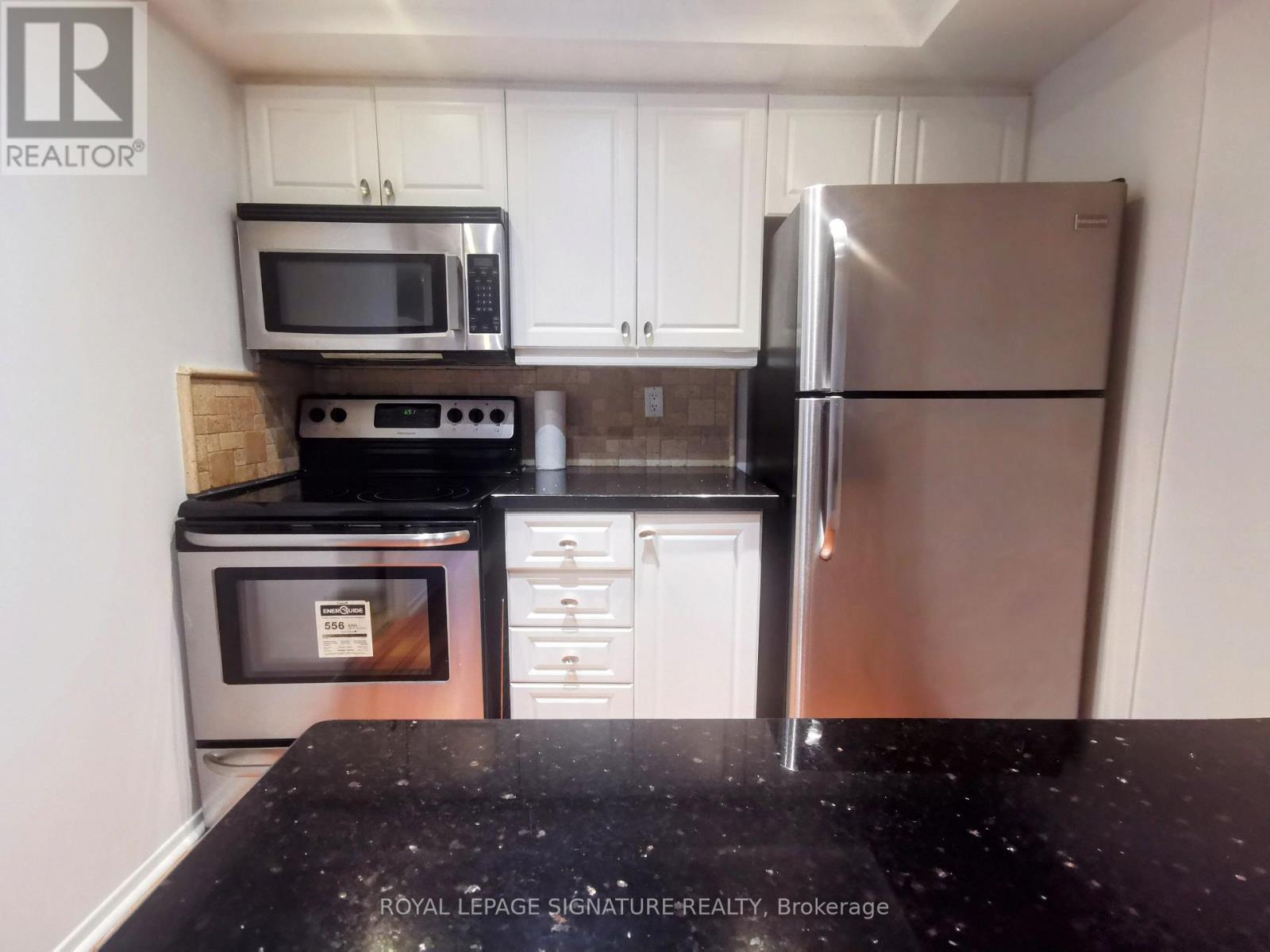 A kitchen with a black counter top and stainless steel appliances.