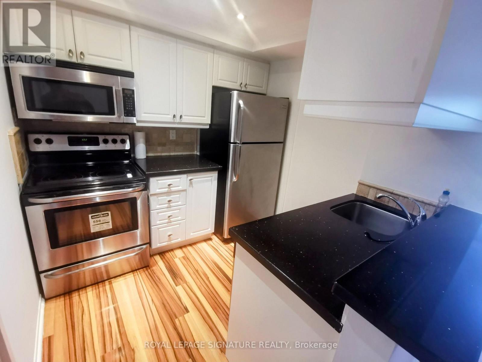 A kitchen with a stove, oven, refrigerator, and sink.