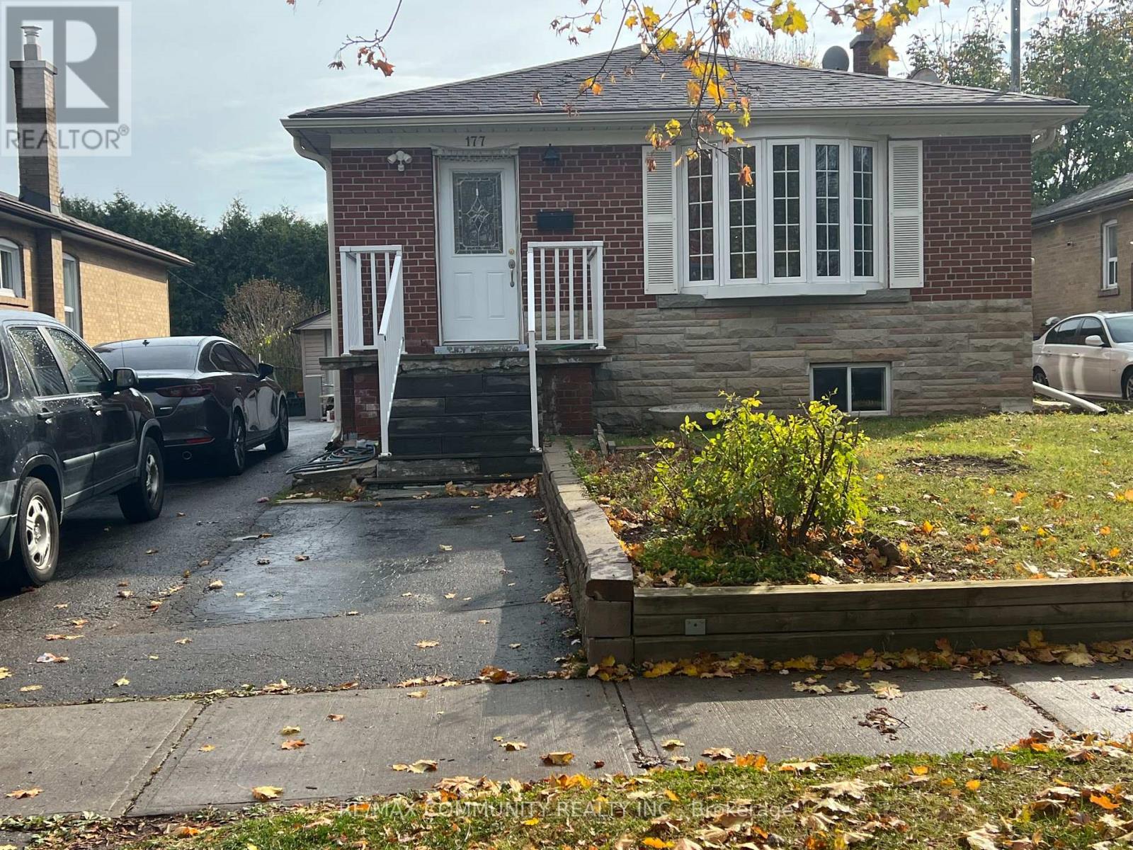 A small brick house with a white door and windows is shown with a car parked in front.