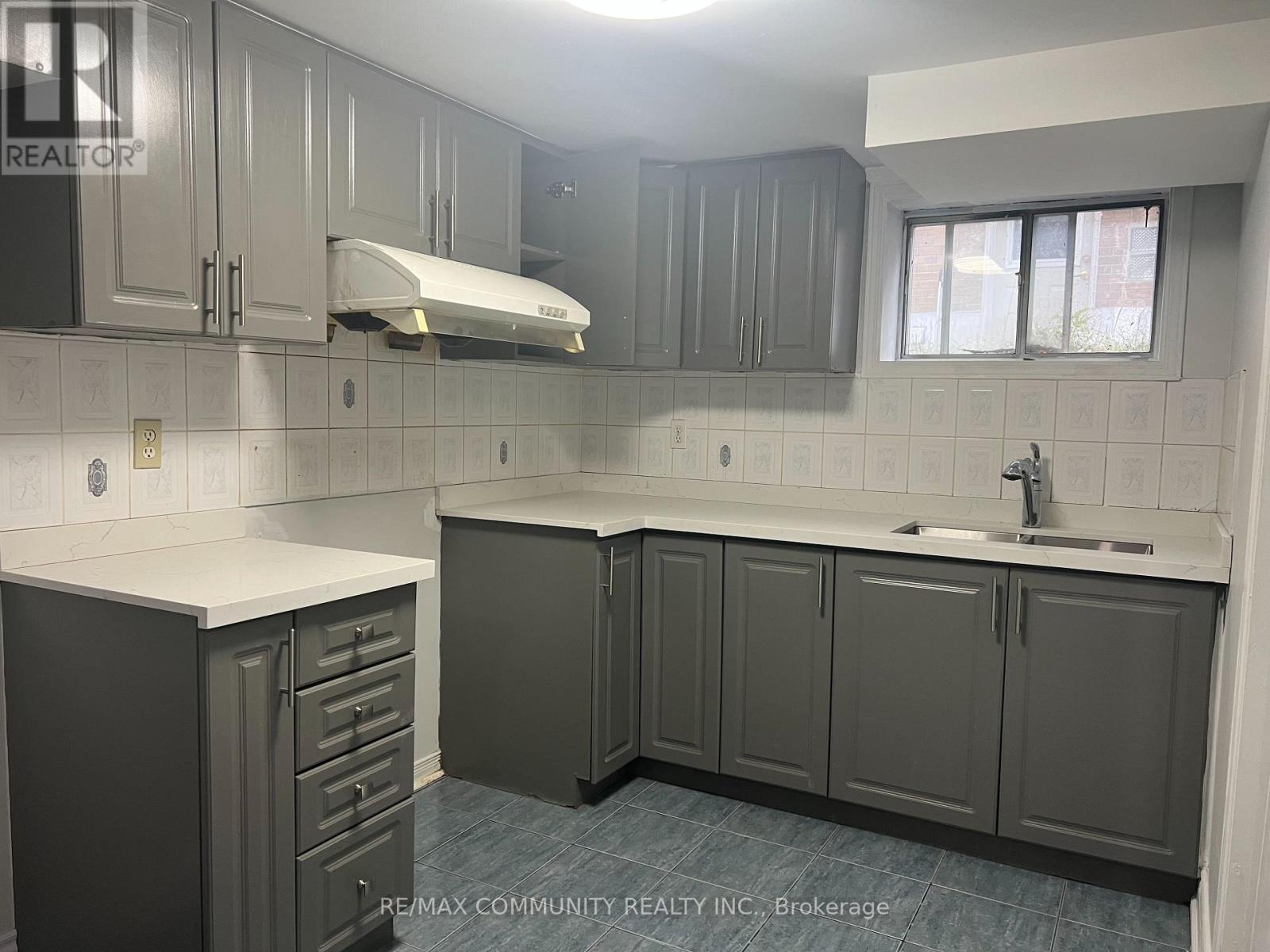 A kitchen with grey cabinets and a white counter top.