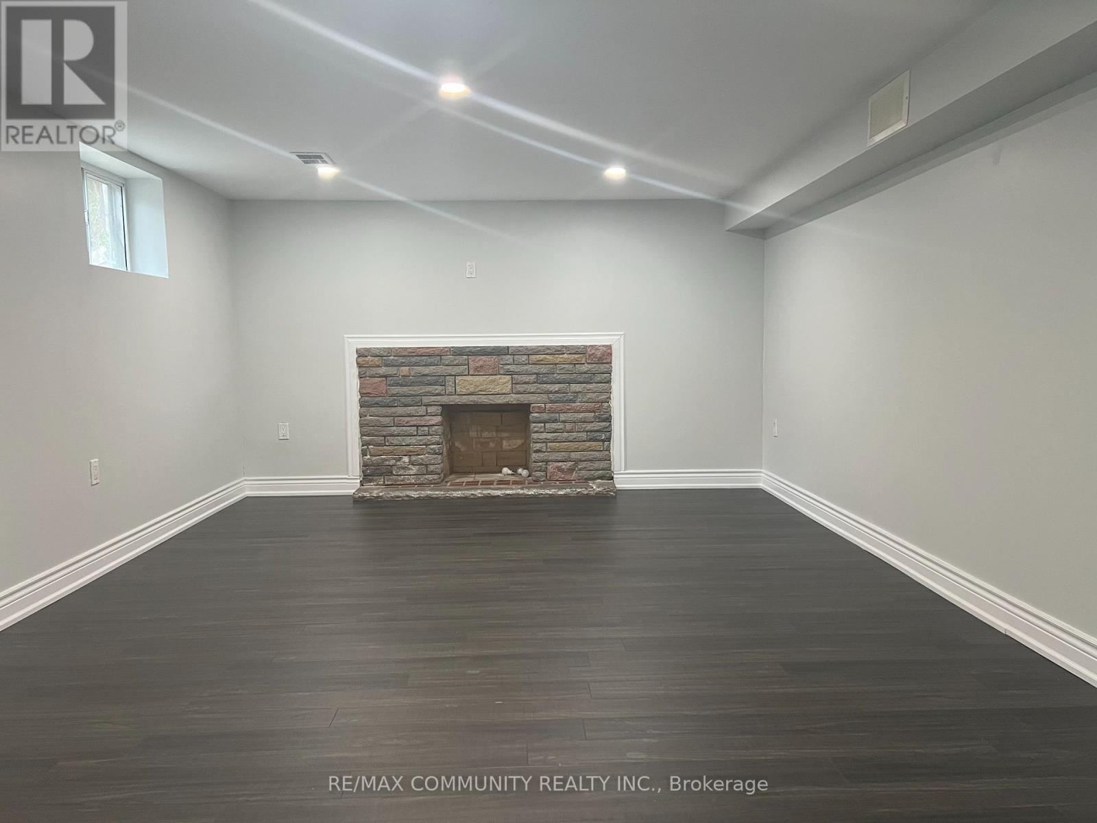 A room with a stone fireplace and wooden floors.