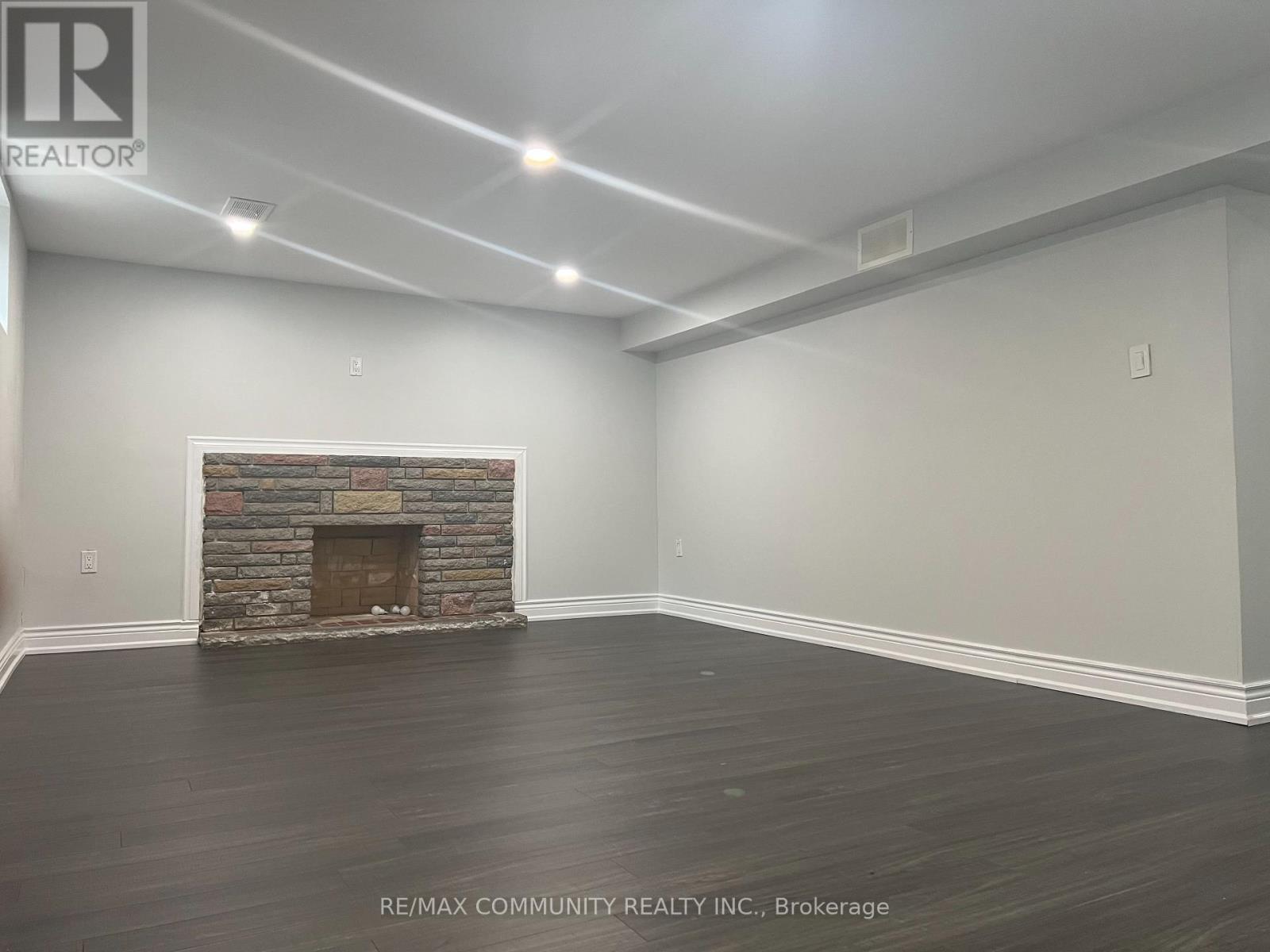 A room with a stone fireplace and wood flooring.