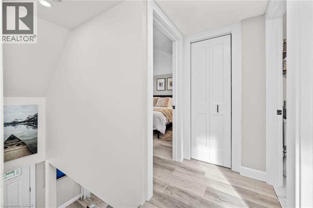 A white bedroom with a bed and a painting on the wall.