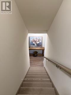 A hallway with a painting on the wall and a bench at the end.