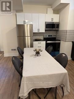 A table with a white cloth and a vase of flowers on it sits in a kitchen.
