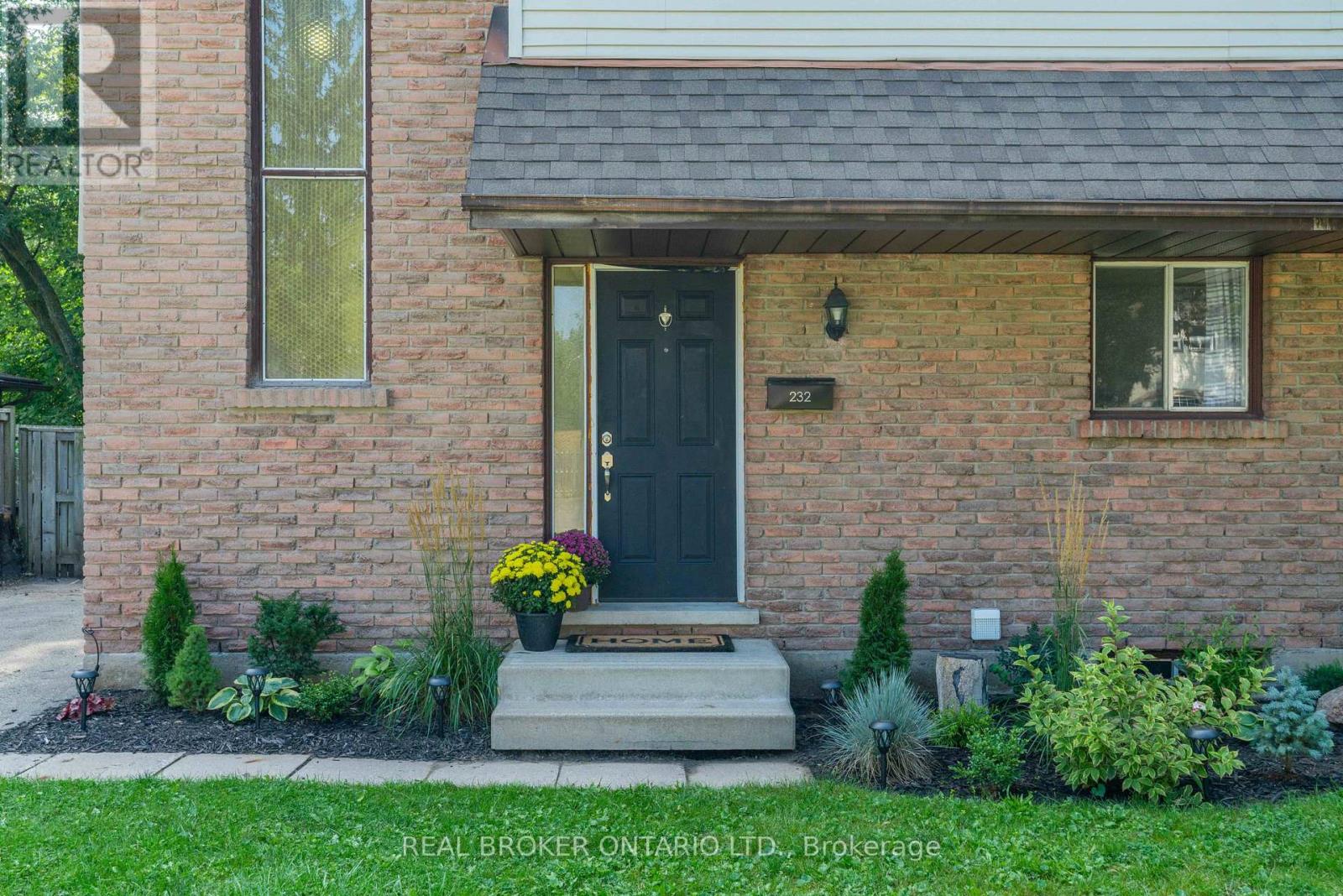 A house with a black front door and a small front yard with plants.