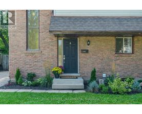 A house with a black front door and a small front yard with plants.