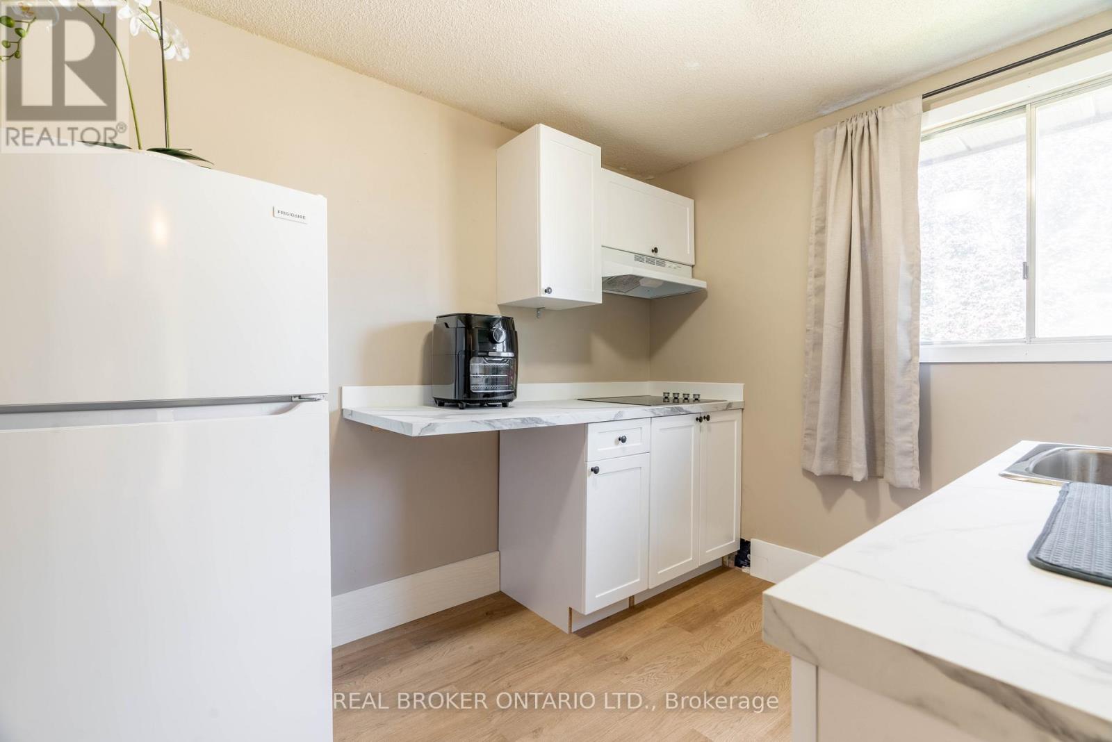 A small kitchen with a white fridge, white cabinets, and a white countertop.
