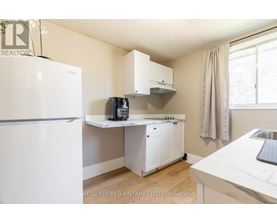 A small kitchen with a white fridge, white cabinets, and a white countertop.