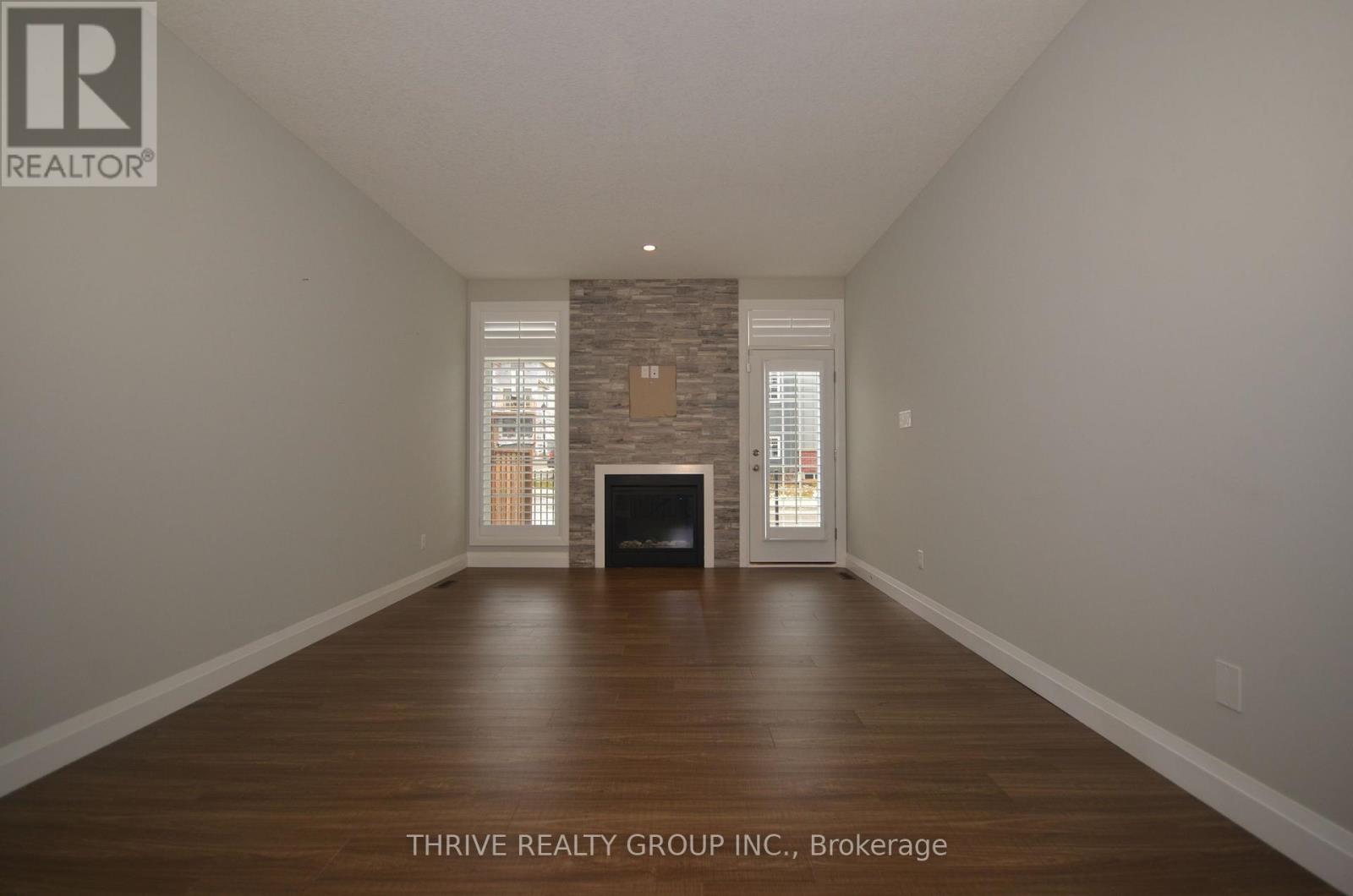 A spacious room with a fireplace and wood flooring.