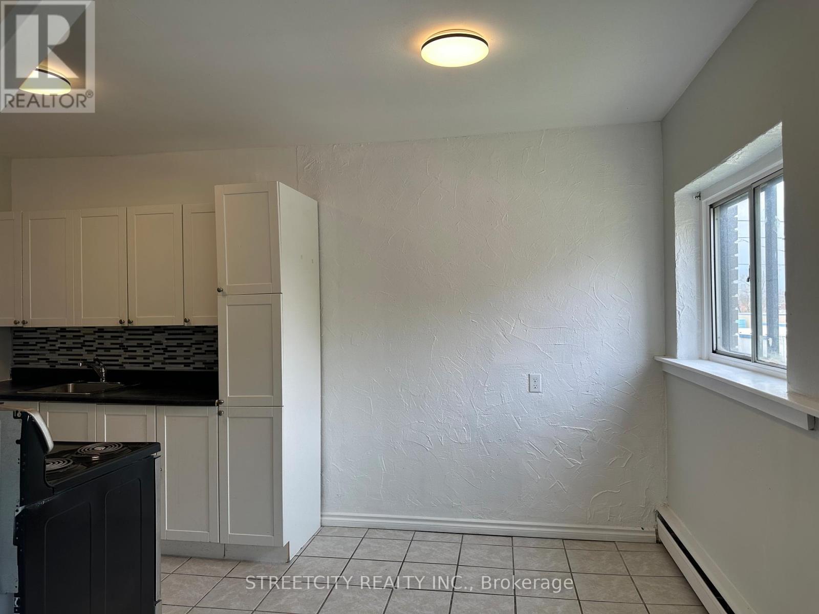 A kitchen with white cabinets and black countertops.