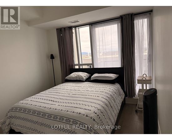 A bedroom with a large bed and a window with curtains.