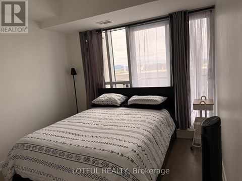 A bedroom with a large bed and a window with curtains.