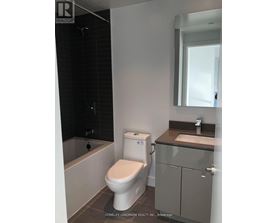 A white toilet in a bathroom with a sink and mirror.