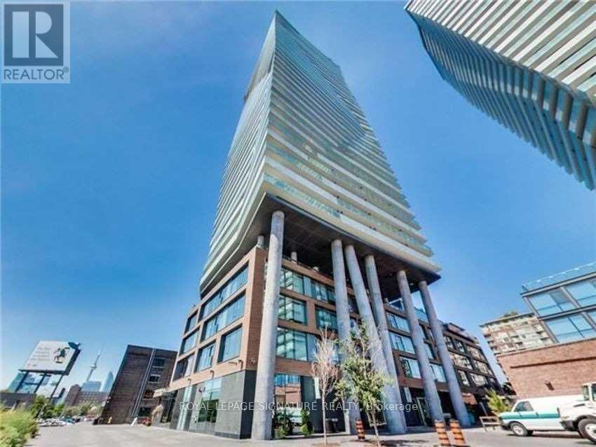 A tall building with a glass facade and a curved top is surrounded by other buildings.
