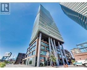 A tall building with a glass facade and a curved top is surrounded by other buildings.