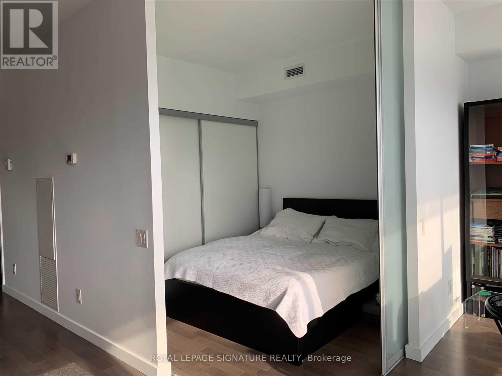 A bedroom with a bed, nightstand, and a cabinet.