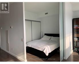 A bedroom with a bed, nightstand, and a cabinet.